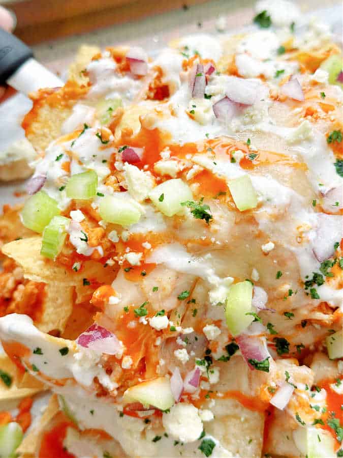 close up of loaded buffalo chicken nachos on the baking sheet