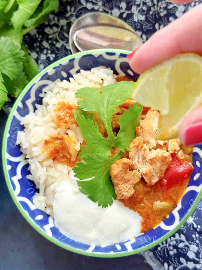 squeezing a lime wedge over the pork curry