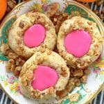 thumbprint cookies with pink icing plated on a vintage china plate