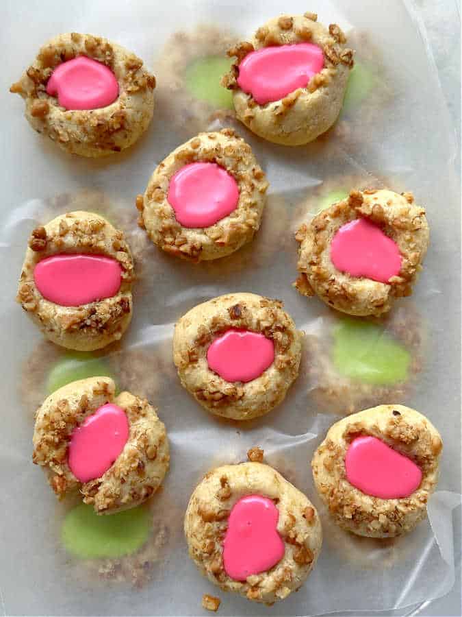 thumbprint cookies with icing stored in a container, separated with wax paper