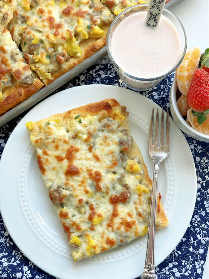 school breakfast pizza plated with fresh fruit and a yogurt smoothie on the side