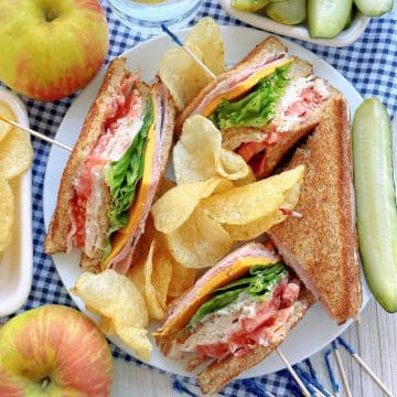 clubhouse sandwich plated with potato chips and dill pickle spear