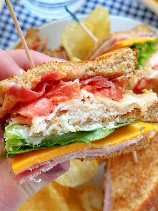 taking a bite of a triangle of a club sandwich