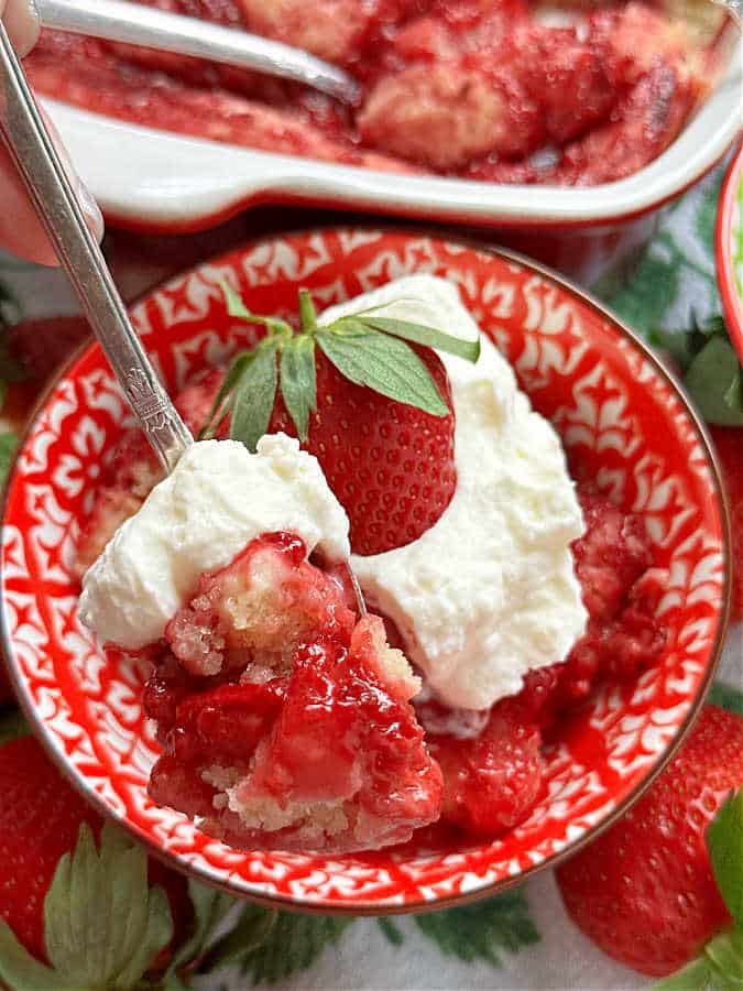taking a bite of strawberry spoon cake topped with homemade whipped cream