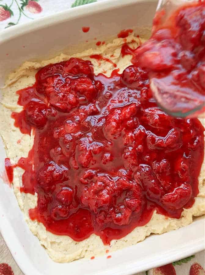 pouring the sugared strawberries over the top of the cake batter