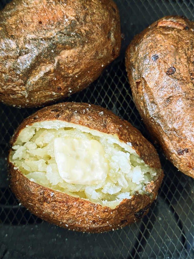 three russet potatoes in the basket of the air fryer