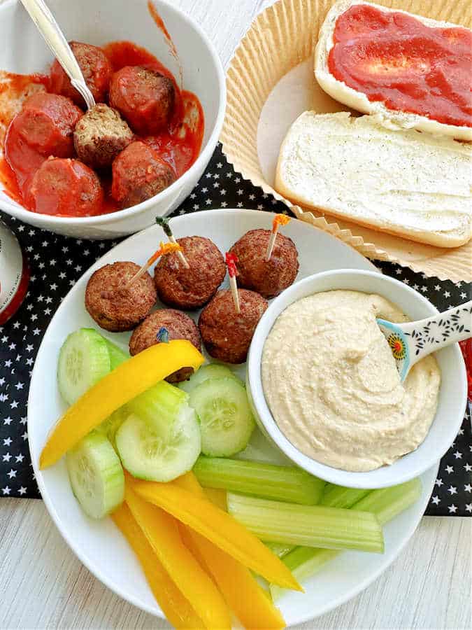 cooked air fryer frozen meatballs shown as a snack with veggies and hummus, or as a meatball sub dinner