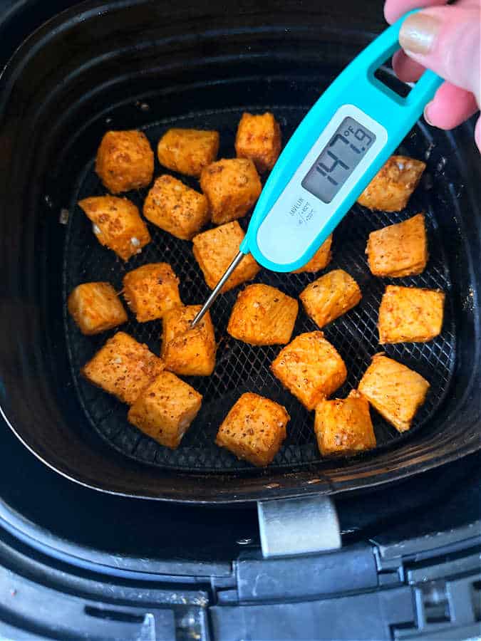 showing the cooked salmon bites in the basket of the air fryer