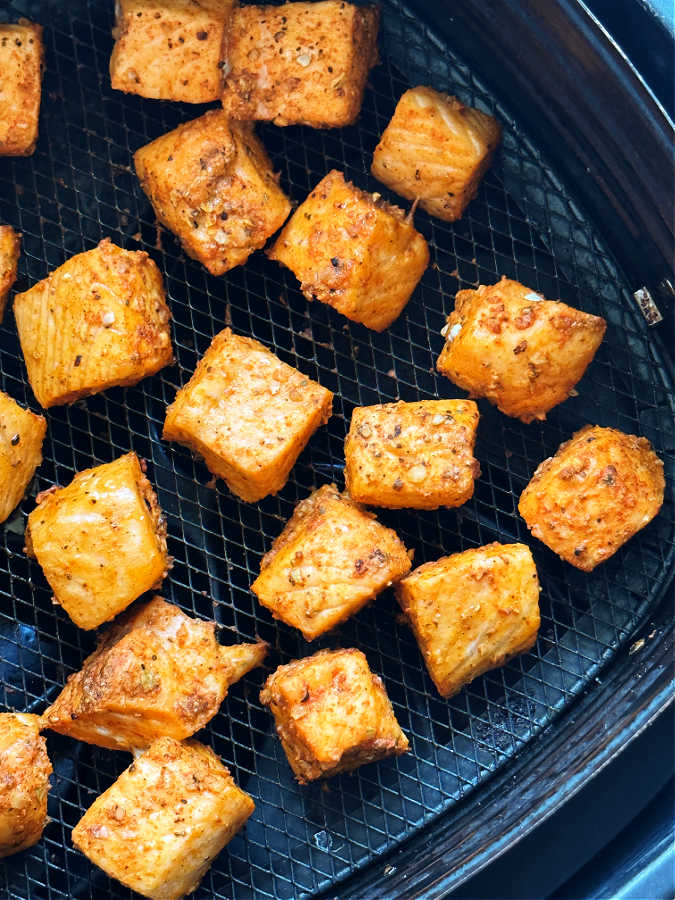 close up of cooked salmon bites in the air fryer basket