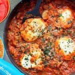 four Spanish eggs cooked in a pan and garnished with cilantro and Manchego cheese