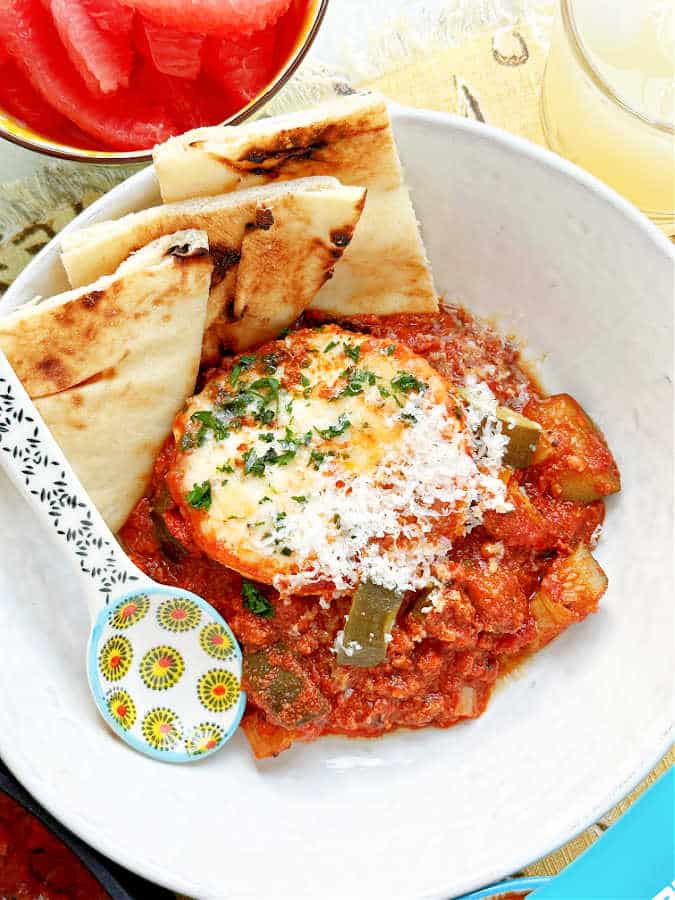 Spanish eggs and sauce with three triangles of Naan bread in a bowl
