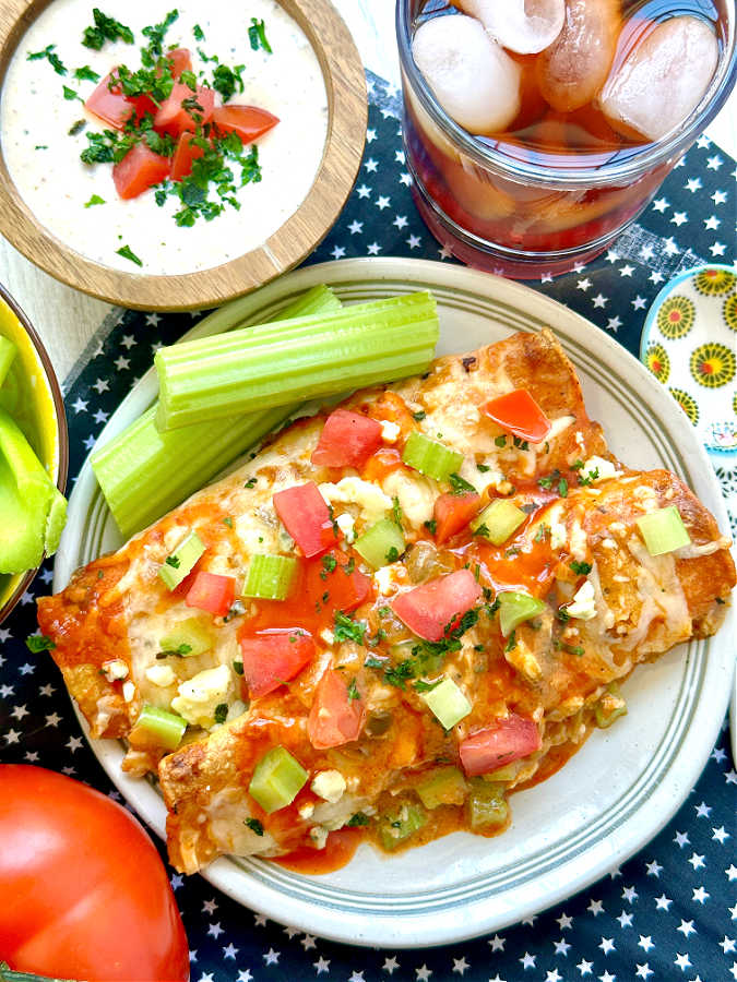 two buffalo chicken enchiladas plated with celery and ranch dressing to dip