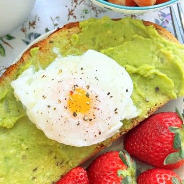 air fryer poached egg plated on a slice of avocado toast and fresh strawberries