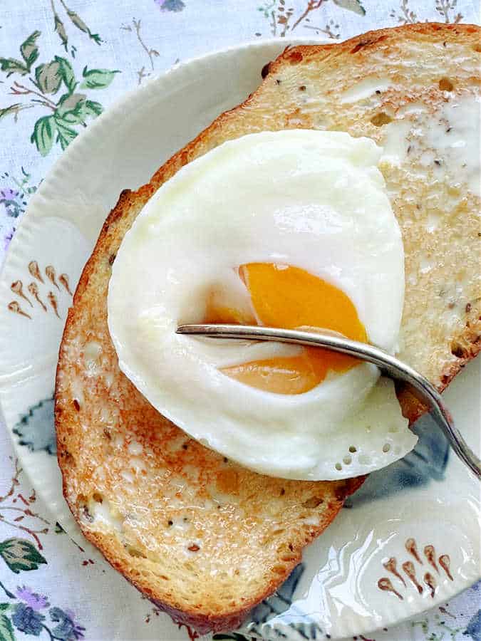 perfectly poached egg on top of a slice of buttery, toasted bread