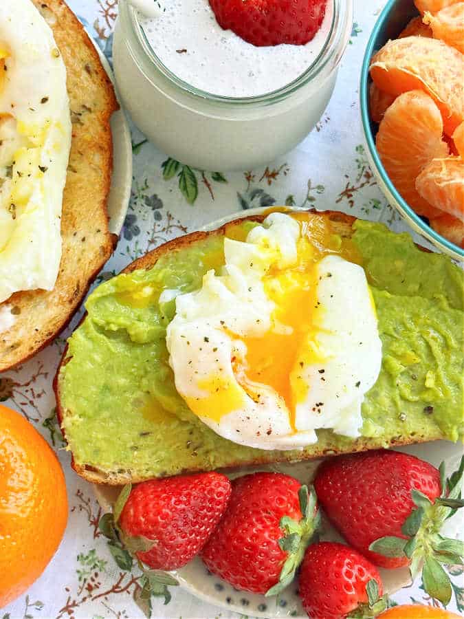 air fryer poached eggs served with avocado toast and fresh strawberries and orange slices