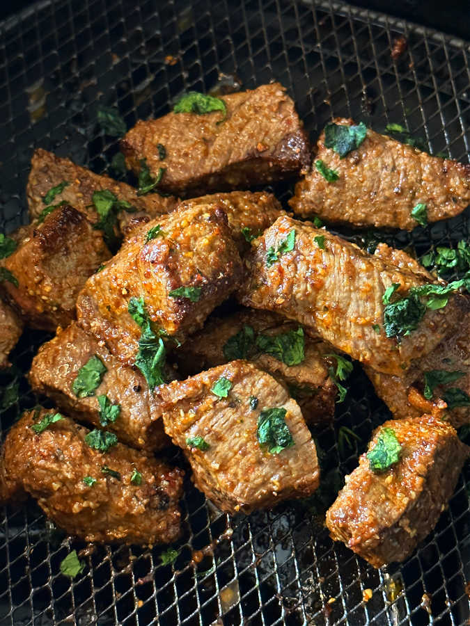cooked steak bites in the basket of an air fryer