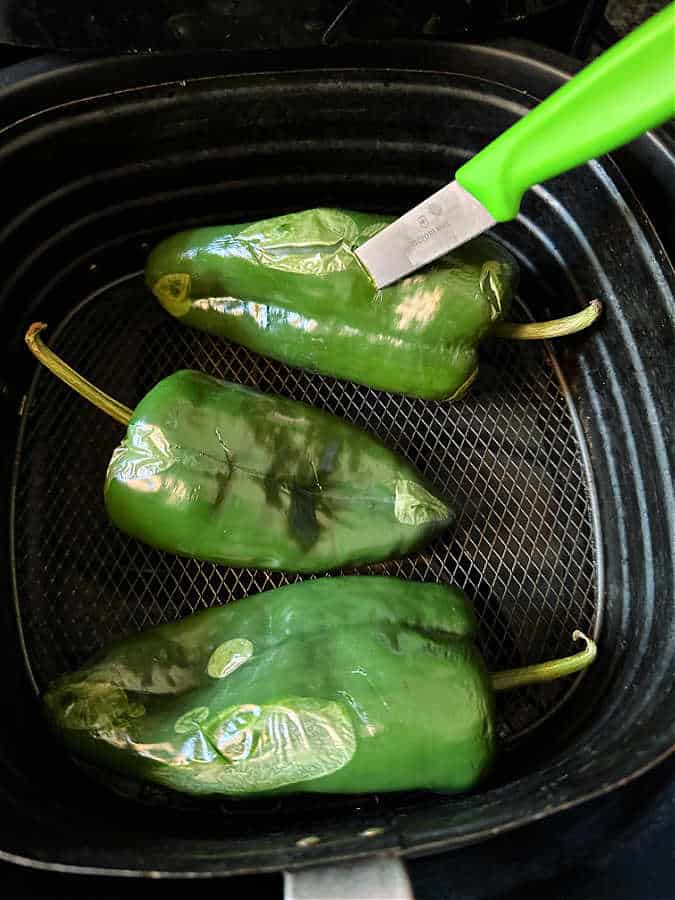 piercing the skin of a roasted poblano pepper