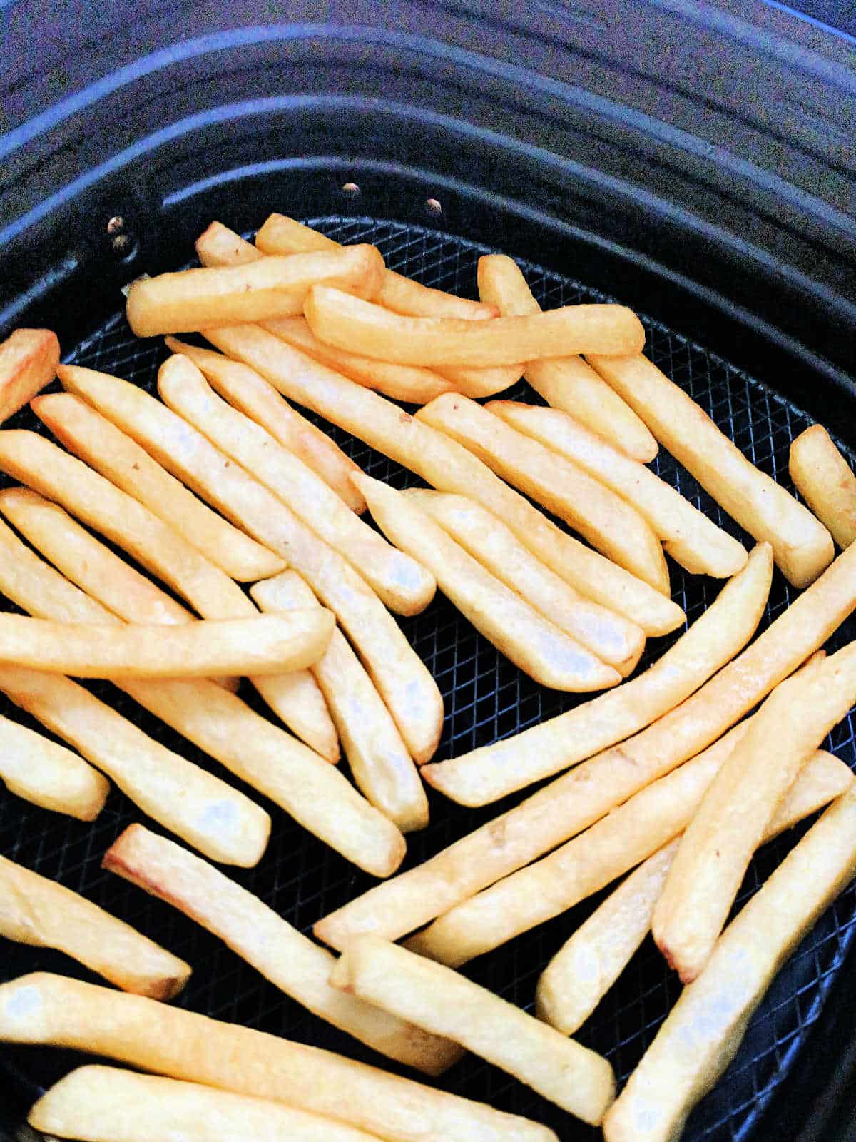 cooked frozen fries in the basket of the air fryer