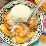 a bowl of peach crisp topped with a scoop of butter pecan ice cream