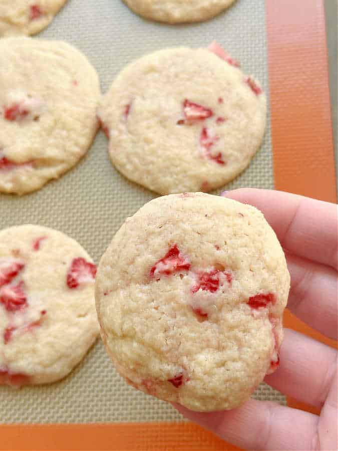 holding a freshly baked strawberry sugar cookie