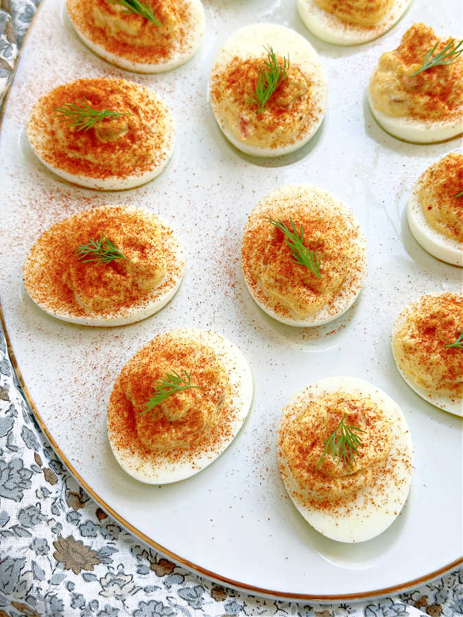 a plate of deviled eggs with relish, garnished with paprika and dill