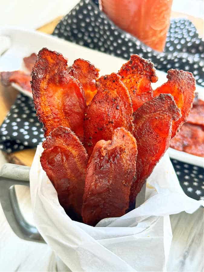 Candied bacon arranged vertically in a serving mug.