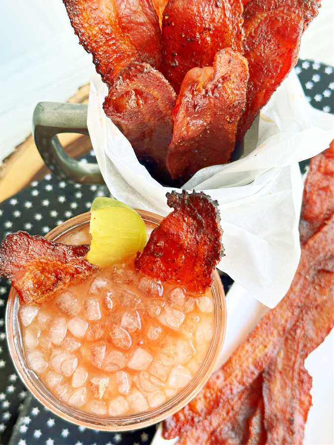 Overhead view of candied bacon as a garnish in a Bloody Mary cocktail.