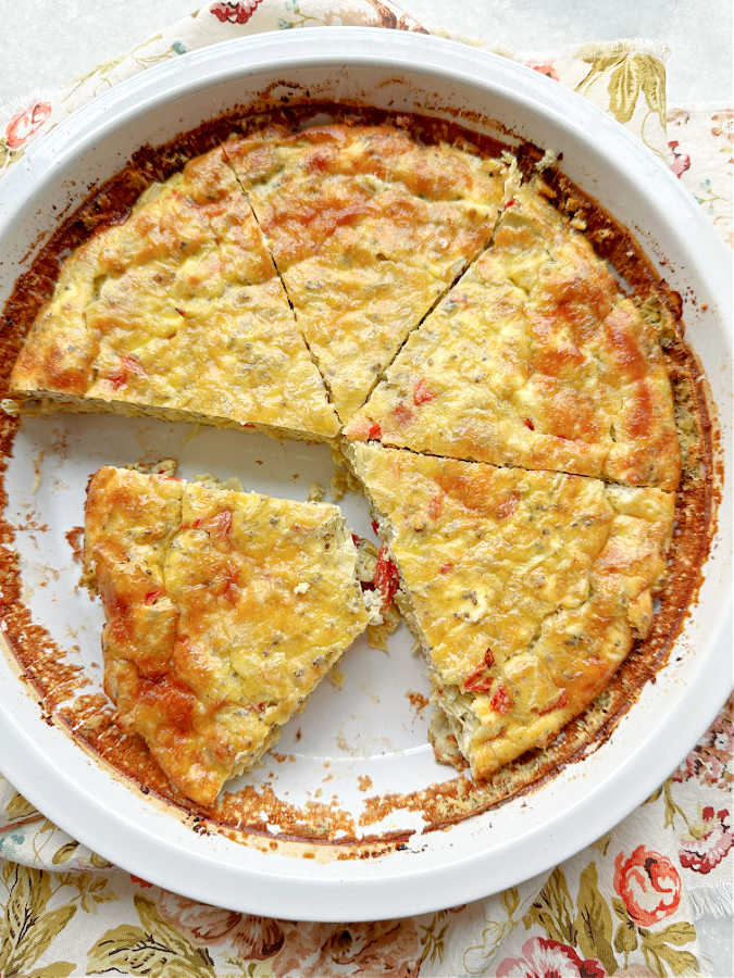 An overhead view of sliced goat cheese quiche in the pie plate that it was baked in.