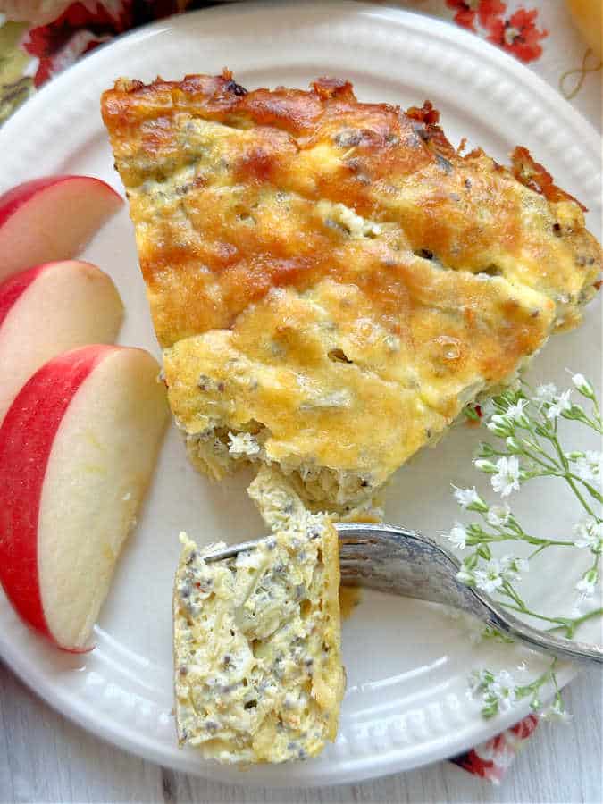 taking a bite of a slice of goat cheese quiche, which is crustless and filled with artichoke hearts, roasted red peppers and chia seeds.