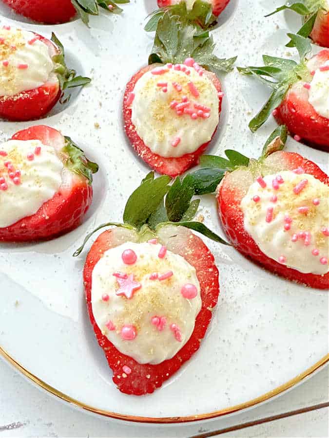 close up view of a fresh strawberry sliced and filled with cheesecake mixture