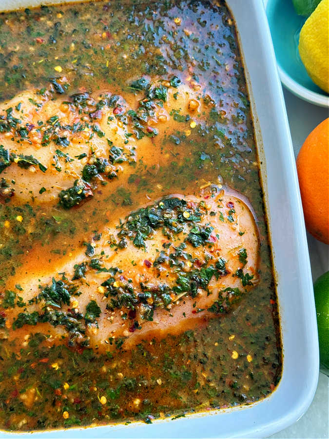 raw chicken breasts being marinated in the citrus marinade