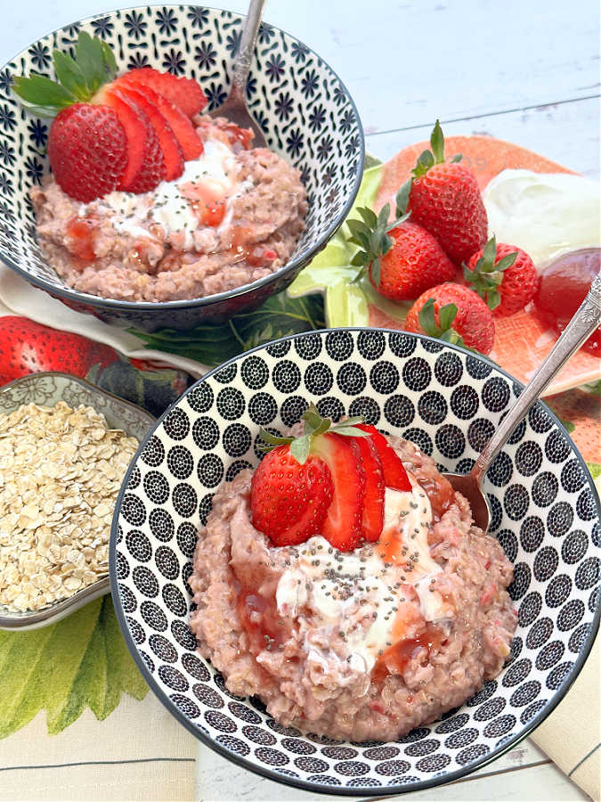 two bowls of strawberry oatmeal, garnished with fresh strawberry slices