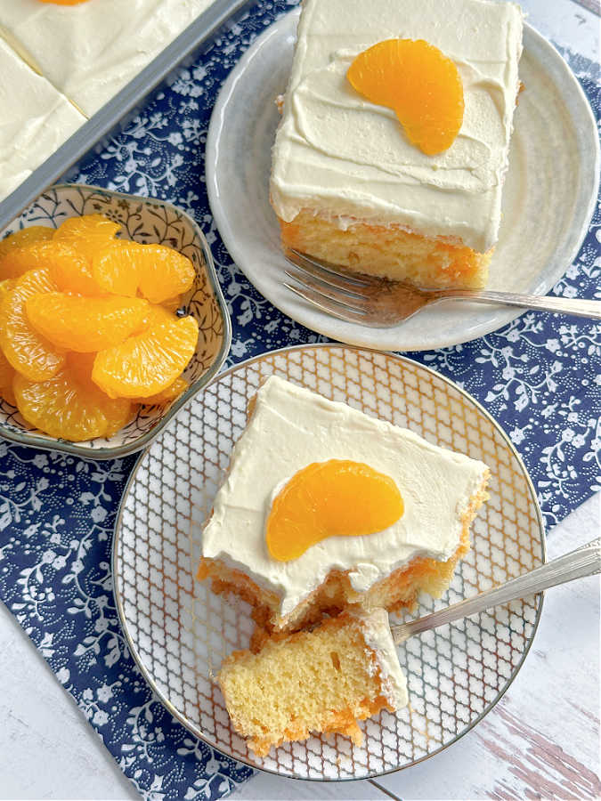 two slices of orange Jello cake plated and garnished with mandarin oranges