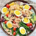 tuna nicoise salad plated with a small bowl of lemon vinaigrette dressing on the side