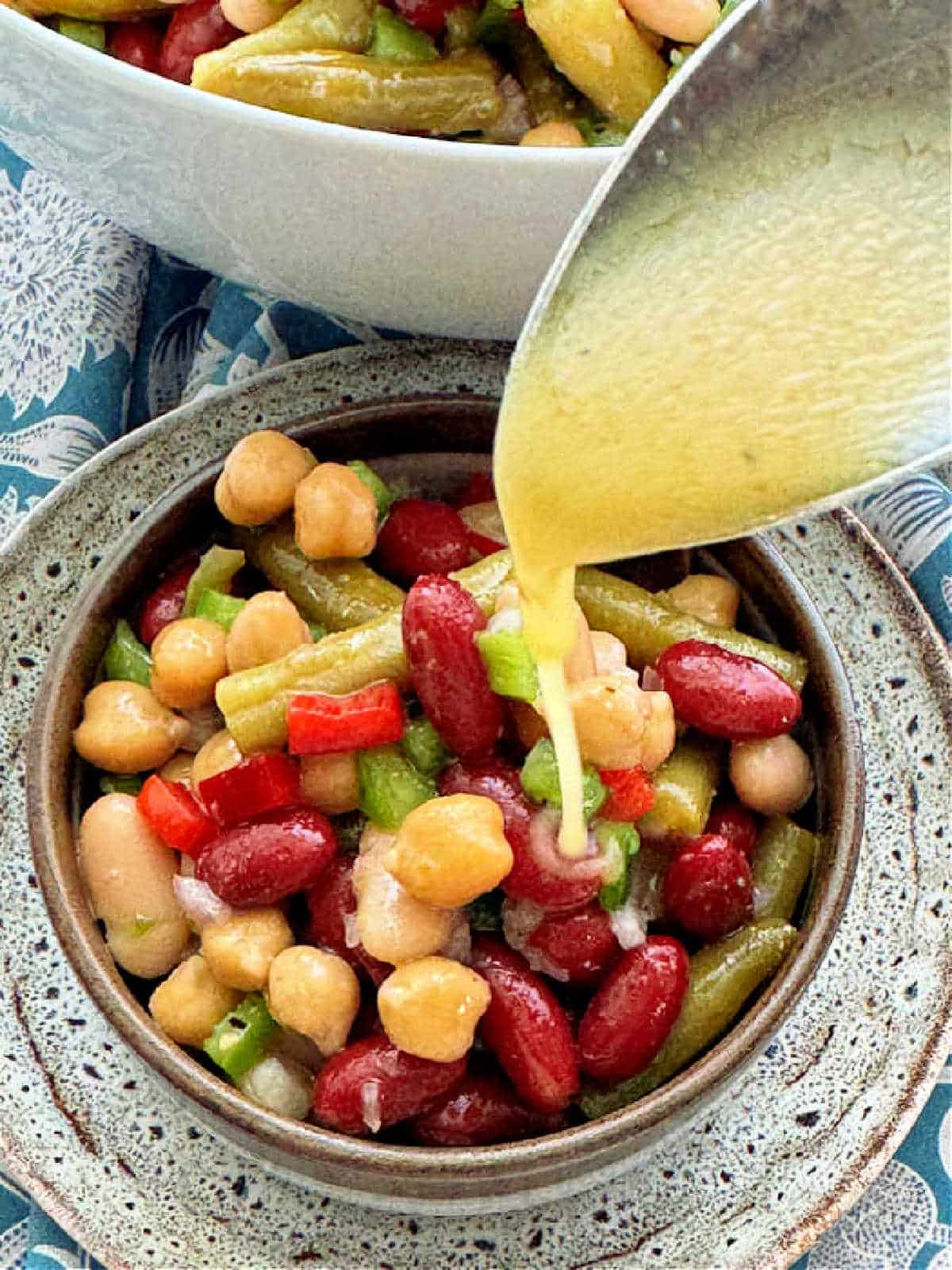 pouring a spoonful of dressing over the bean salad