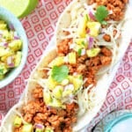 three plated pork tacos topped with fresh pineapple salsa