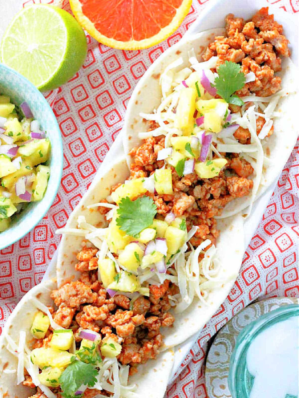three plated ground pork tacos topped with fresh pineapple salsa