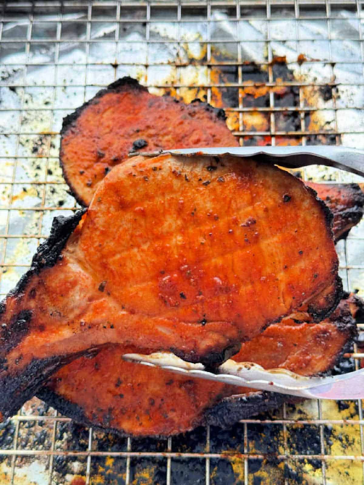 holding a broiled pork chop with metal tongs