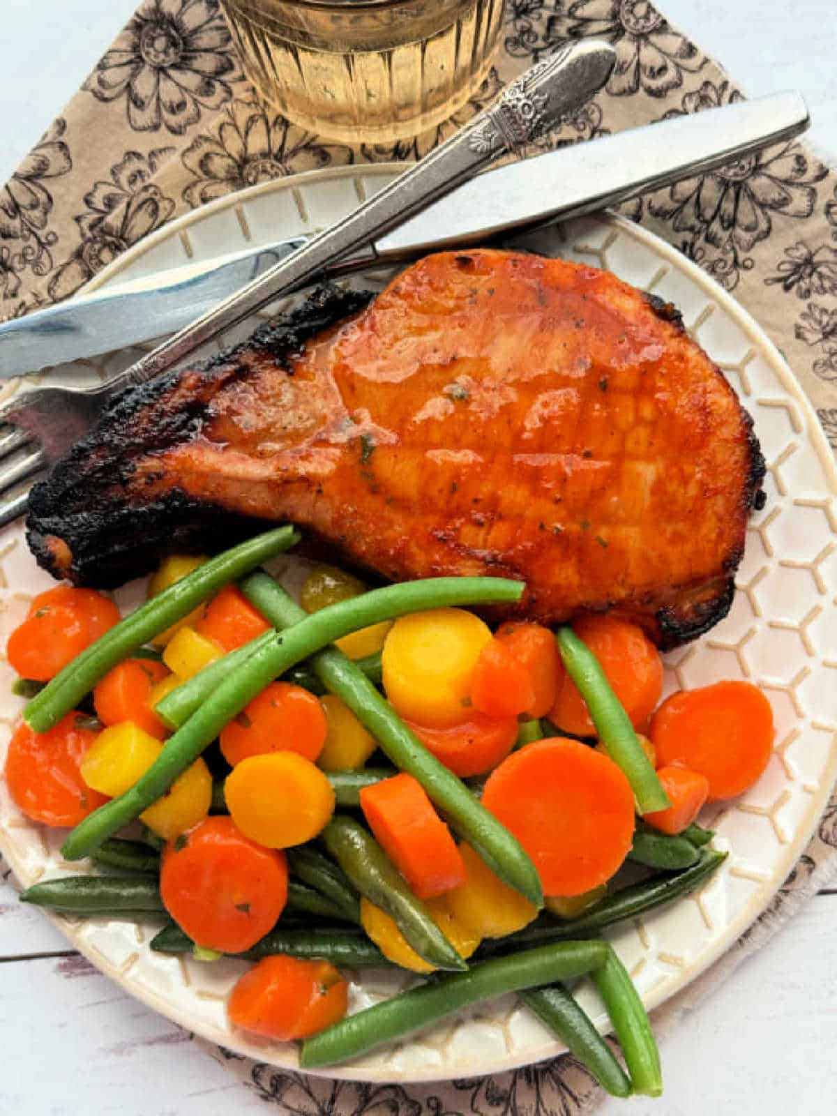 perfectly seasoned broiled pork chop plated with mixed veggies