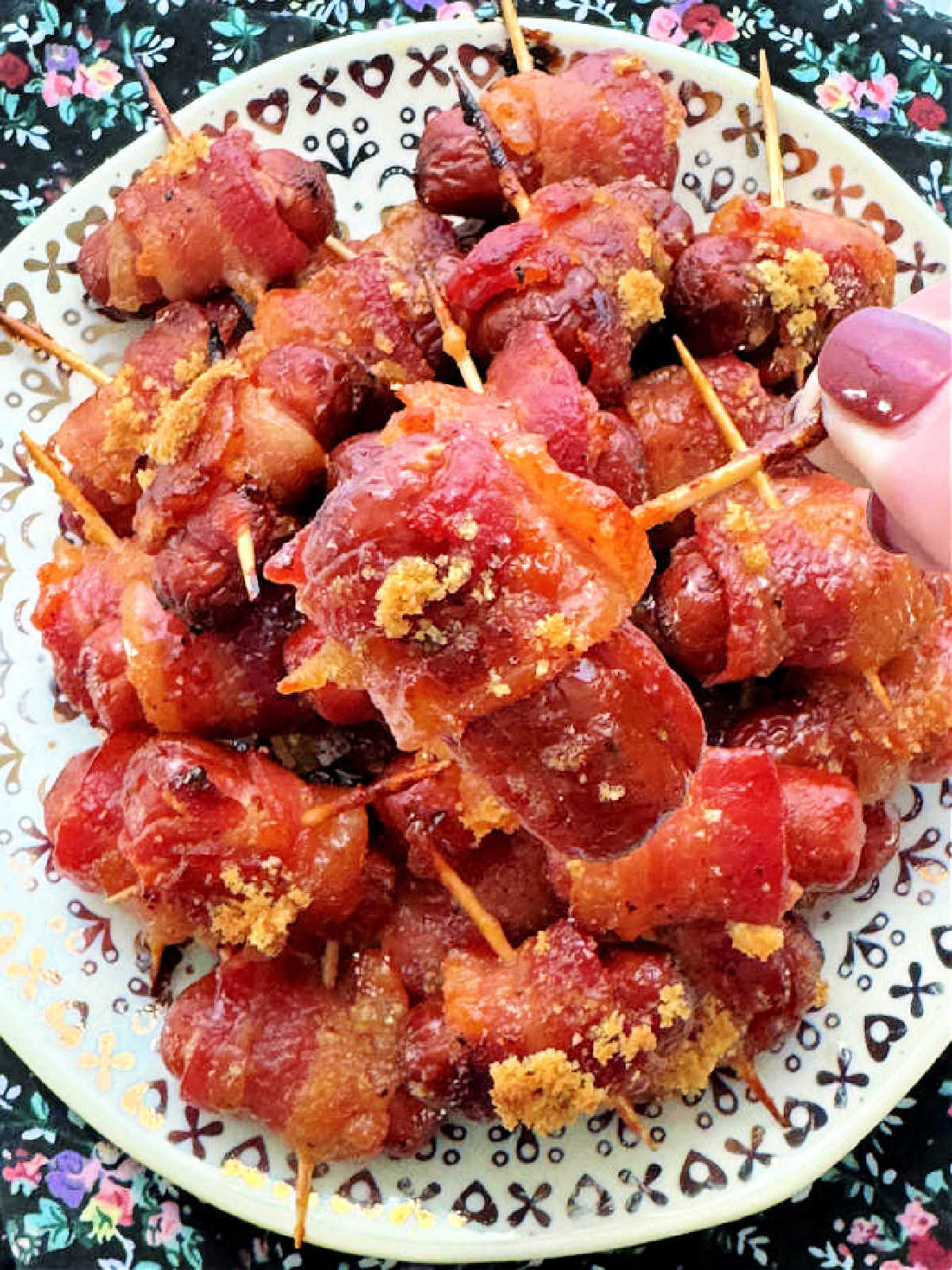 holding a bacon wrapped smoky by its toothpick to show a closer view