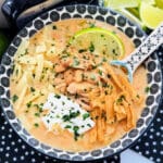 a bowl of white chicken chili garnished with lime, sour cream and cilantro