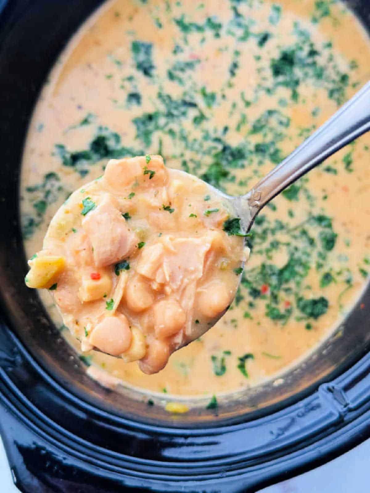 serving a ladle of white chicken chili from the crockpot