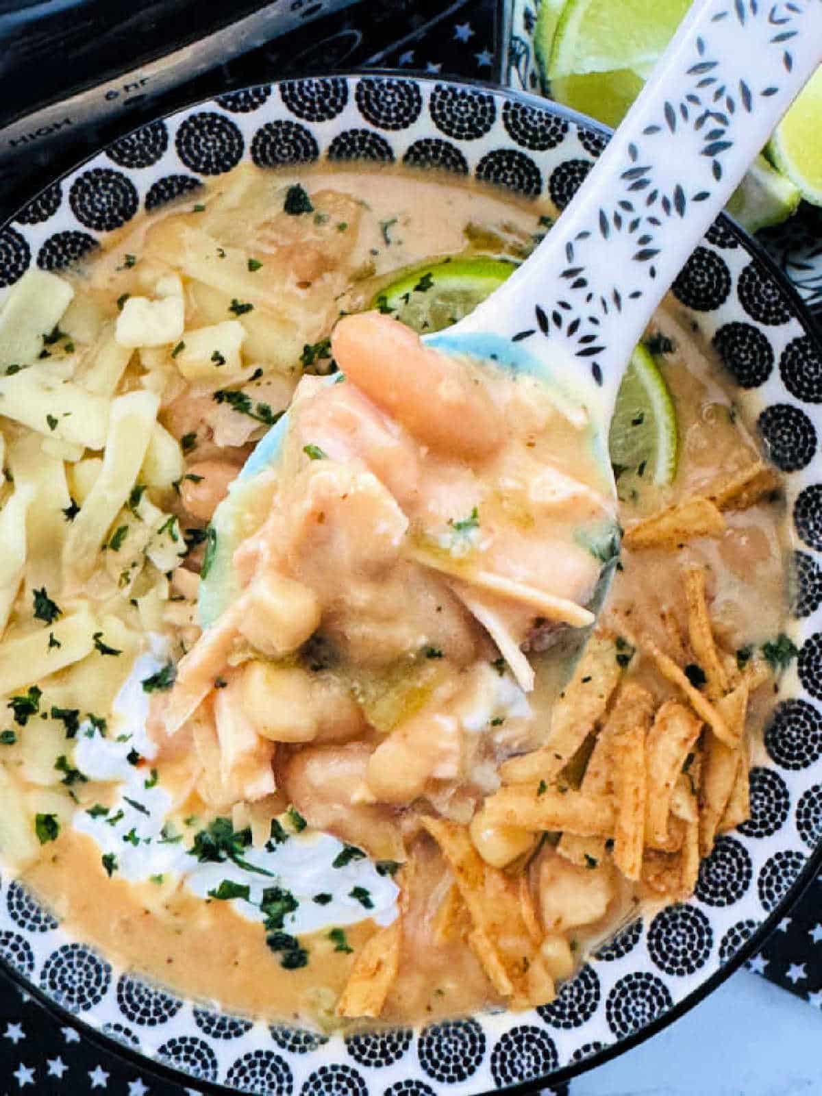 lifting a spoonful of white chicken chili from the serving bowl