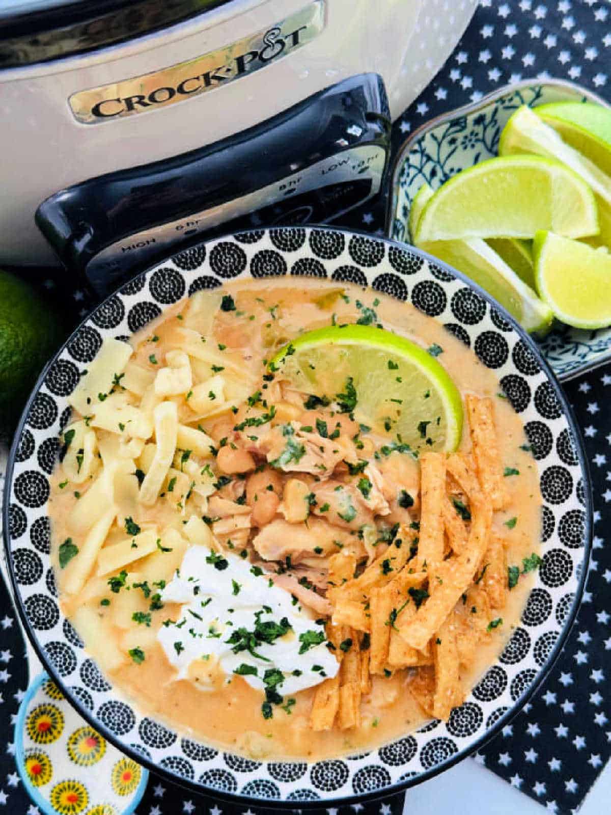a serving bowl of white chicken chili pictured in front of the Crockpot it came from