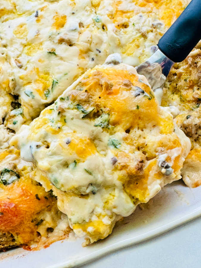 serving a slice of biscuits and gravy casserole from the baking dish