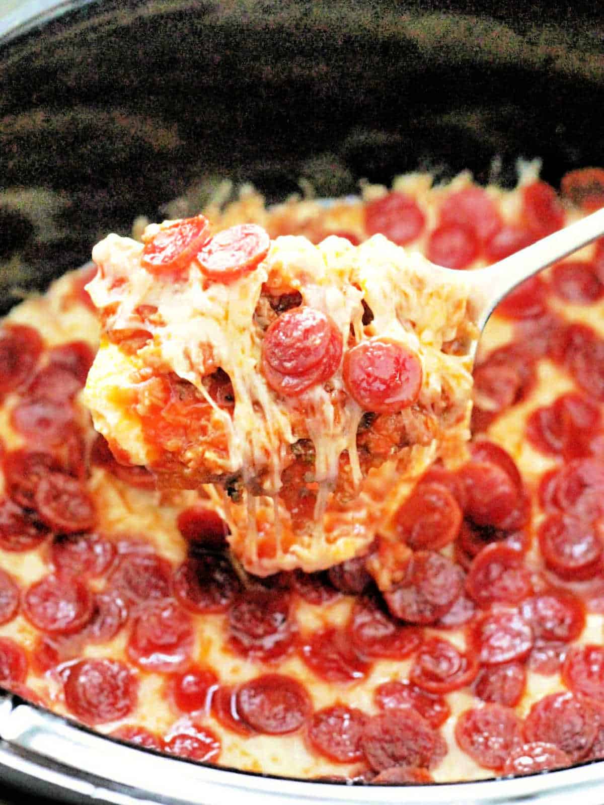 serving a spoonful of pizza dip from the slow cooker