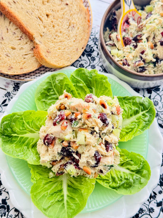 a large scoop of cranberry chicken salad plated on top of leaves of gem lettuce