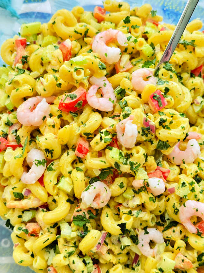bright yellow shrimp macaroni salad in a large serving bowl
