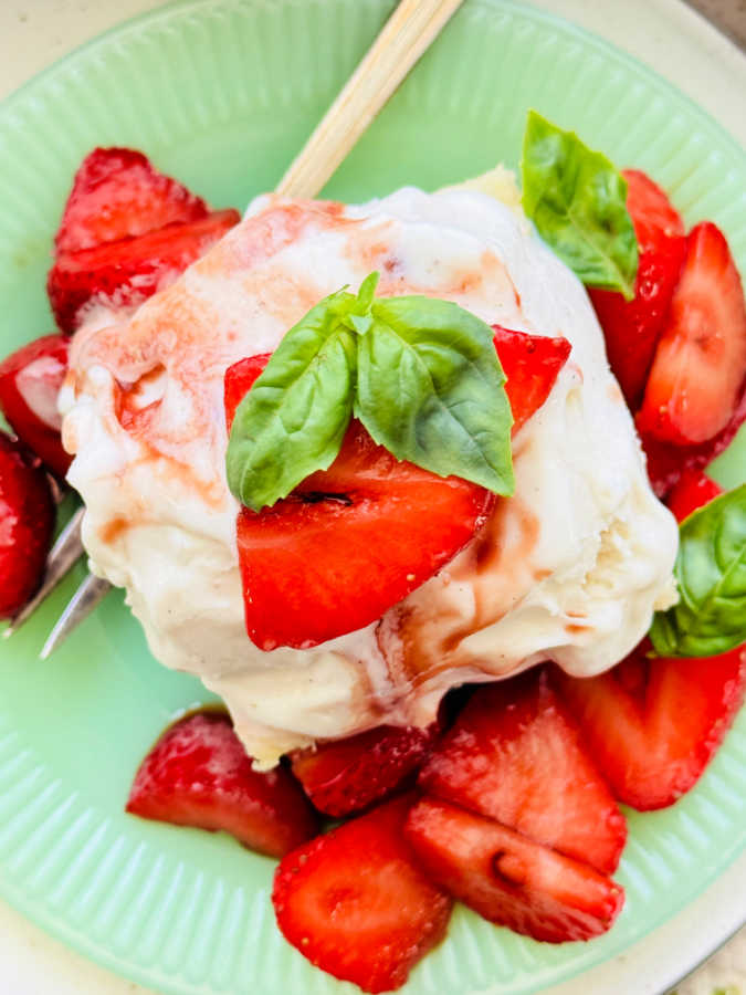a plated slice of balsamic strawberry shortcake, garnished with fresh basil