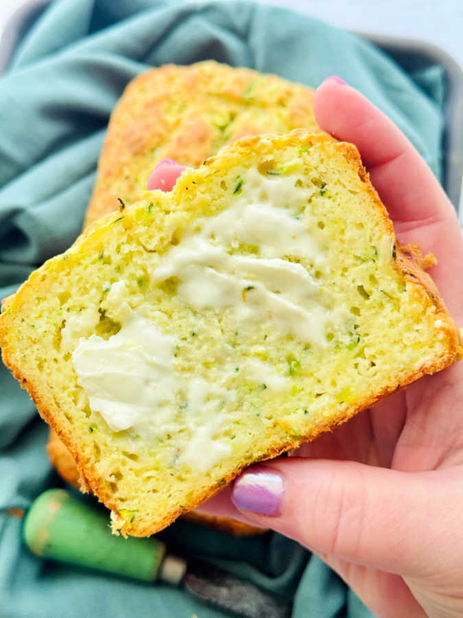 a thick slice of zucchini quick bread spread with butter